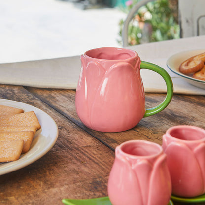 Pink Tulip mug on a table with biscuits and more pink mugs in the foreground