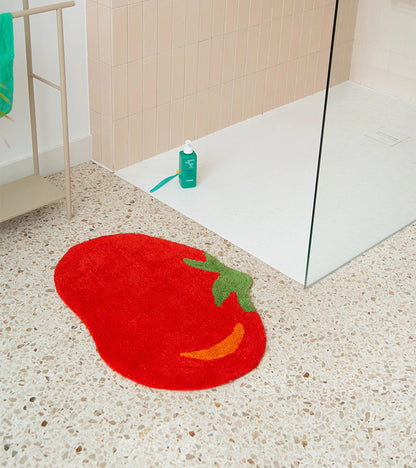 Tomato rug in red on the floor in front of a shower with glass and pink tiles