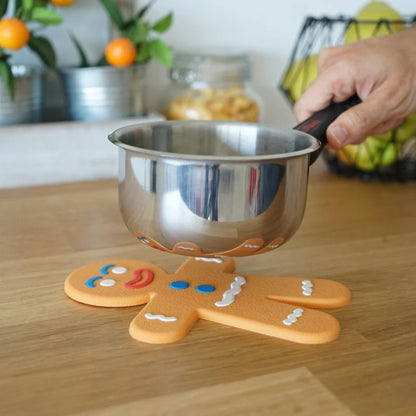 Ginger Man trivet shaped like a gingerbread man, with a steel saucepan resting on top.