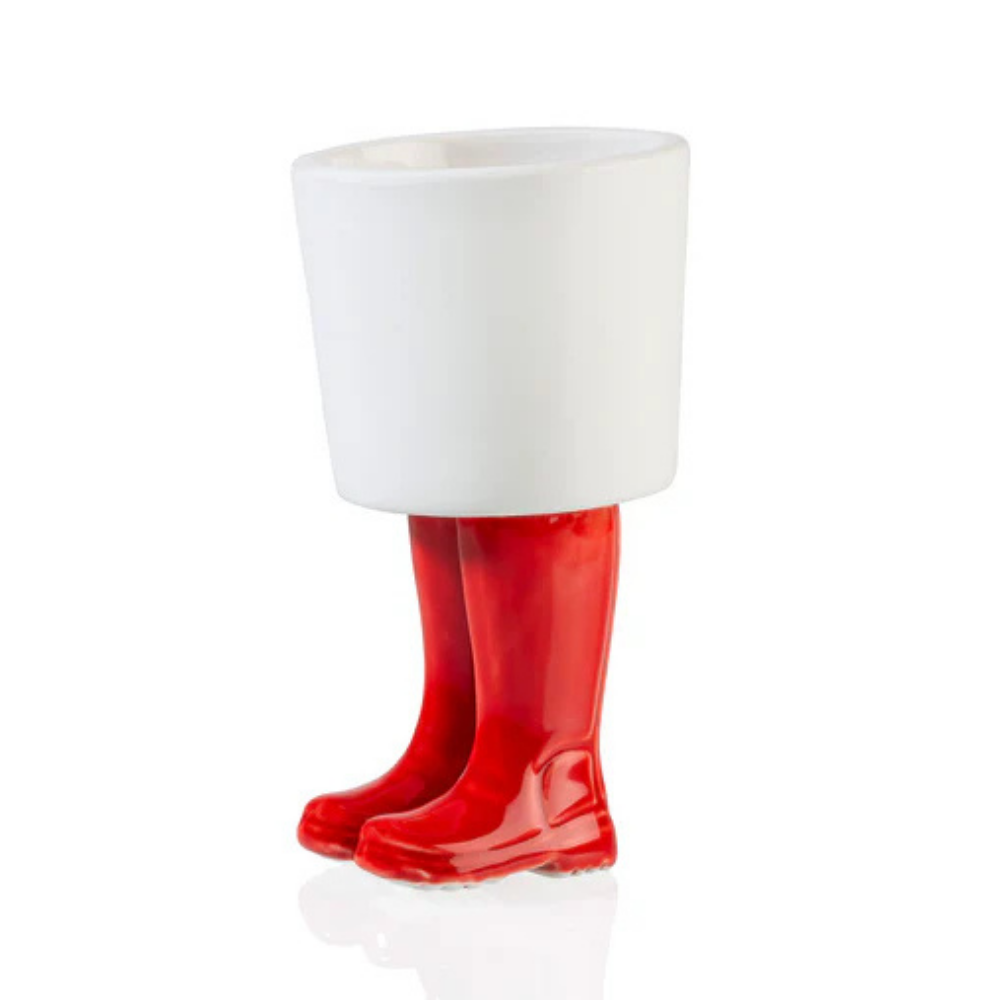 Vaso Piccolo Stivali Wellington: un vaso bianco che poggia su due stivali di gomma rossi, vuoto.