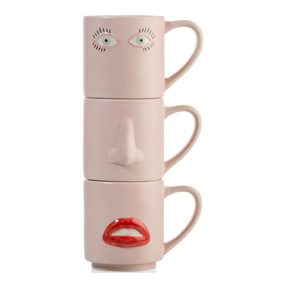 Tazze Surreali: three pink mugs stacked to form a face, with eyes, nose and red lips printed on each.