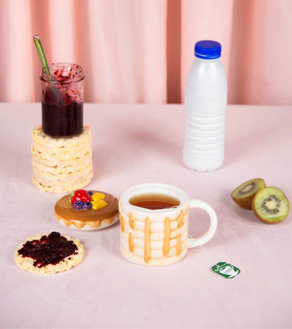 The pancake mug on a breakfast table with jam, kiwi and a bottle of milk