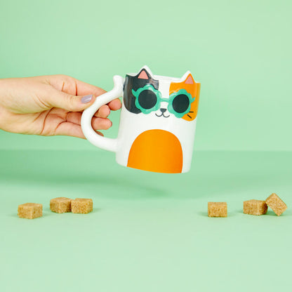 Tazza Cool Cat Calico: una mano regge la tazza a pelo tricolore con occhiali, sfondo verde.