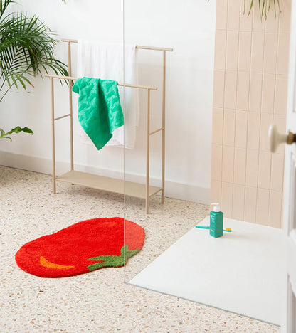Tomato rug in red near a towel rack holding a green towel