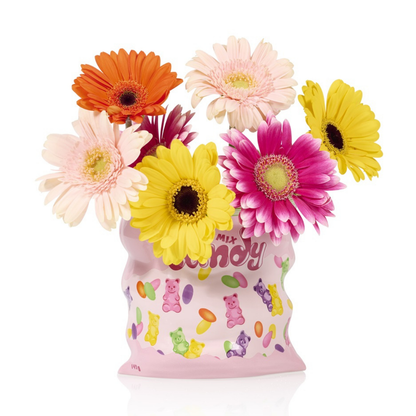 Candy vase shaped like a pink bag, styled with yellow, orange and fuchsia gerberas.