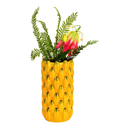 The yellow banana-textured vase filled with ferns and pink tropical flowers