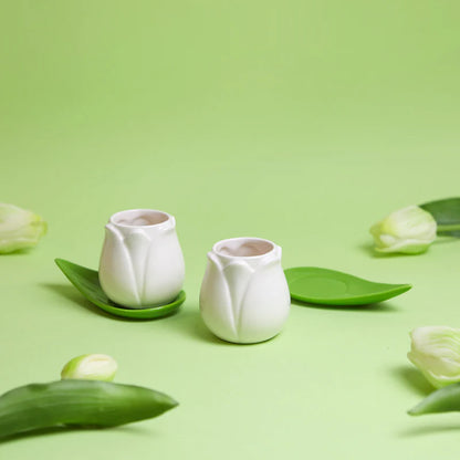 Tulip Coffee Cup Set: the white cups on green background scattered with tulip petals.