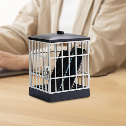 Phone Jail black and silver cage closed on a desk, with a person seated in the background.
