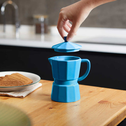 Blue Moka mug on a wooden table with biscuits, lid resting beside it