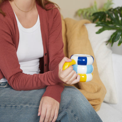 Floats Gialla mug held by someone sitting on a sofa in jeans and a cardigan