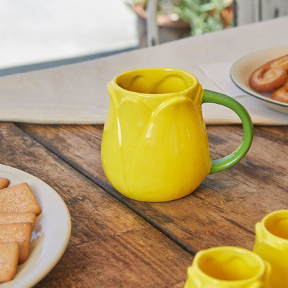 Yellow Tulip mug on a wooden table with biscuits and more mugs