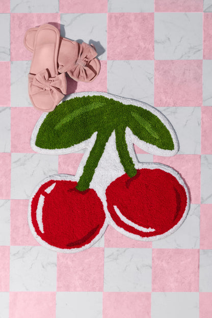 Cherries rug on a pink checkerboard floor, with a pair of sandals nearby