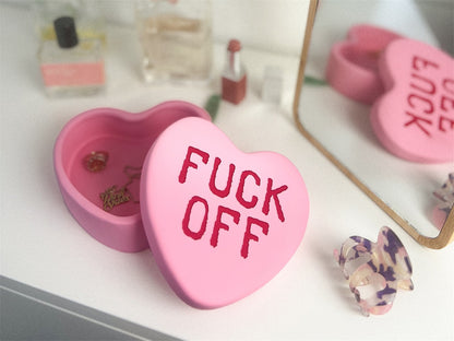Fuck Off heart box in pink, open on a dressing table, reflected in the mirror.