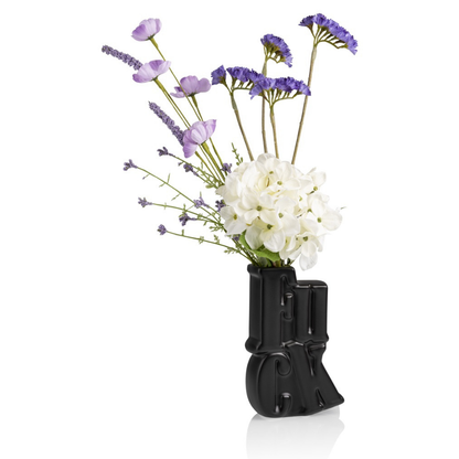 Fuck vase in black, shaped like a raised middle finger, styled with purple and white flowers.