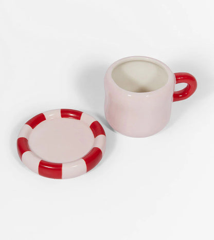 Love mug in white with a red and white striped saucer beside it