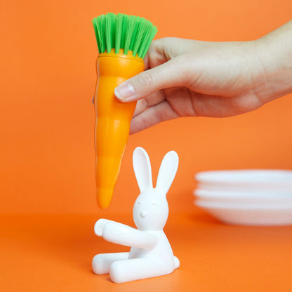 Bunny dish brush held in a hand above the seated rabbit