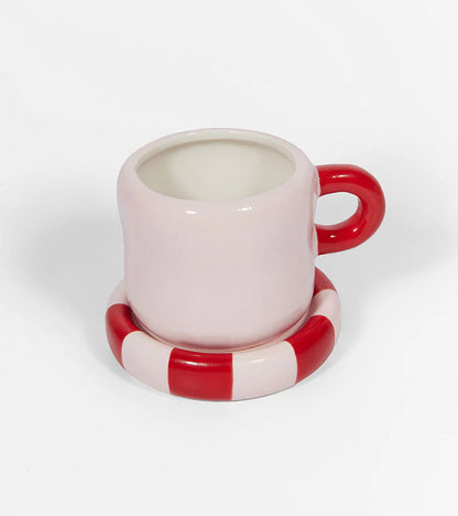 Pink mug with a red handle and a red-and-white striped saucer