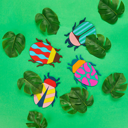 Beetle coasters scattered among tropical leaves on a green background, without glasses.