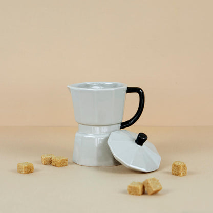 Grey Moka Mug on a beige background with brown sugar cubes, lid resting beside it