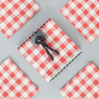 Napkin holder seen from above, filled with red and white checked napkins.