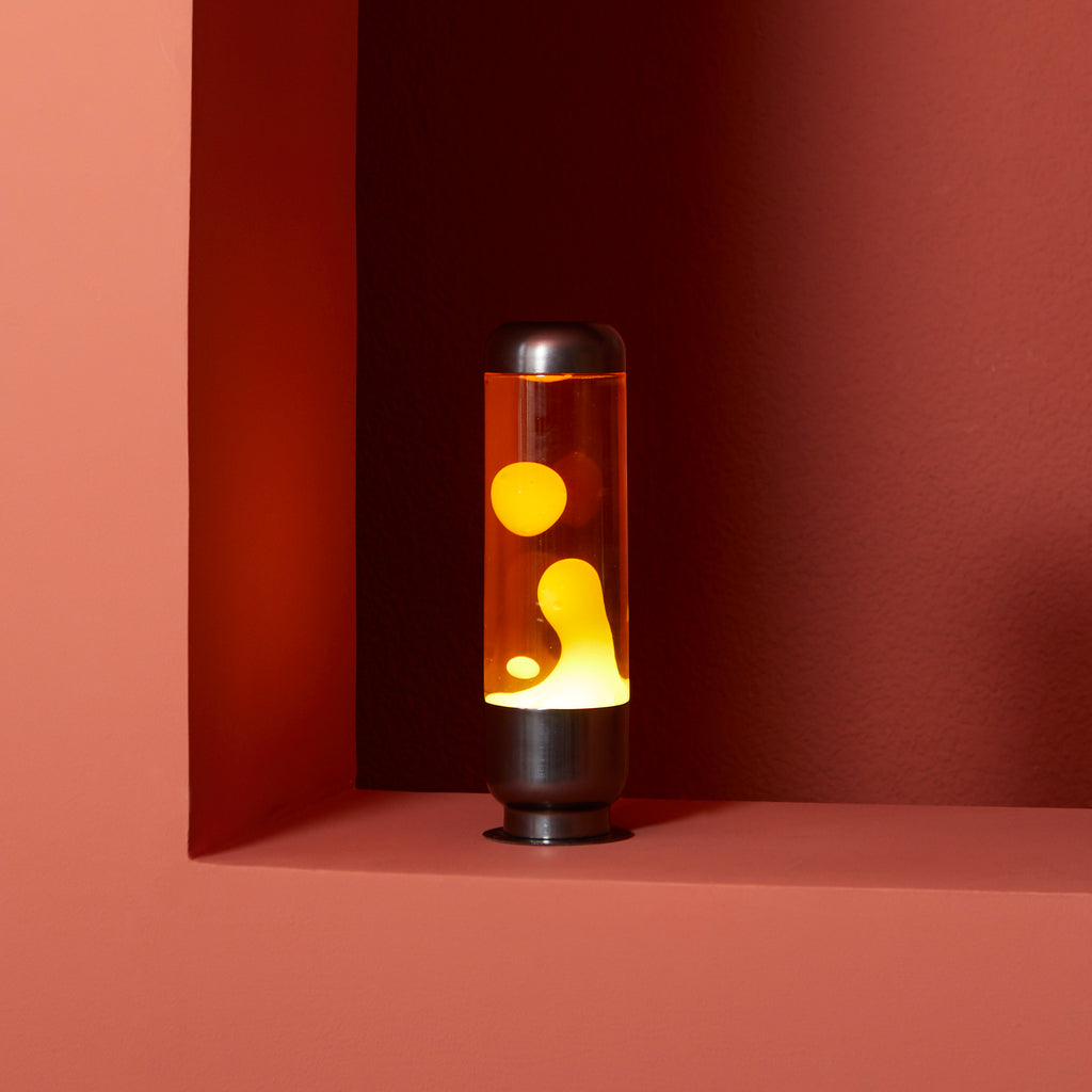 Lampada Lava Capsule: la lampada accesa gialla e arancione in una nicchia rosa.