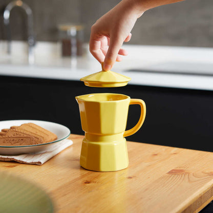 Yellow Moka mug, a hand lifting the lid off the mug