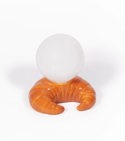 Croissant lamp in caramel tone with a white sphere on top, on a white background