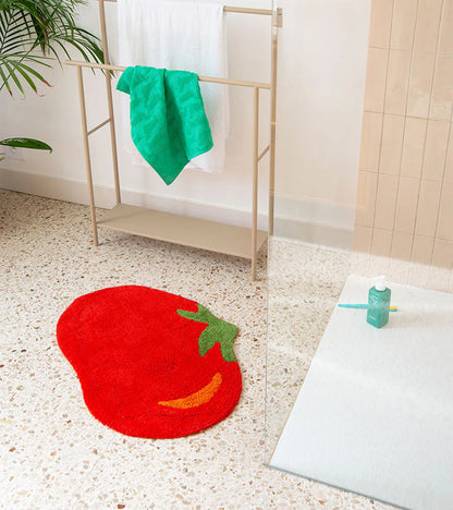 Tomato rug in red at the foot of a white bathtub with gold taps