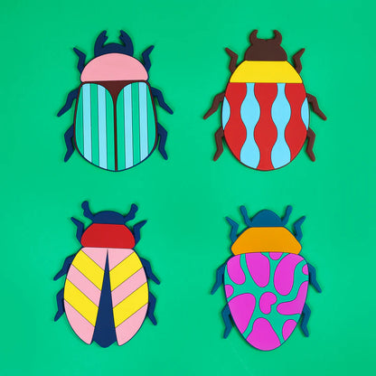 Beetle coasters in four different patterns, laid out in a row on a green background.