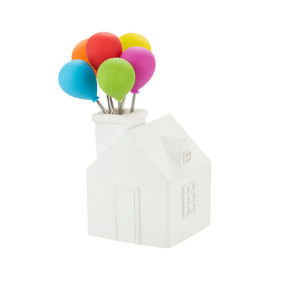 Cocktail forks shaped like colourful balloons, placed in the chimney of a small white house.