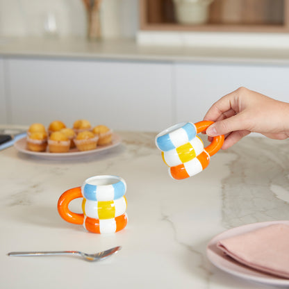 Float cup set, a hand lifting one mug over a marble counter, muffins in the background