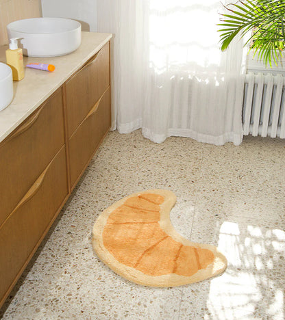 Croissant rug in honey tone on a wooden floor near a bathtub