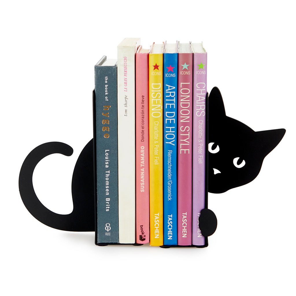 Black cat-shaped bookend peeking out from behind a row of books, on white