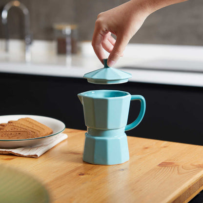 Mint green Moka mug on a wooden table with biscuits, lid resting beside it