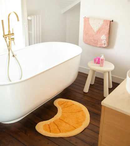 Croissant rug in honey tone in front of a staircase and a potted plant