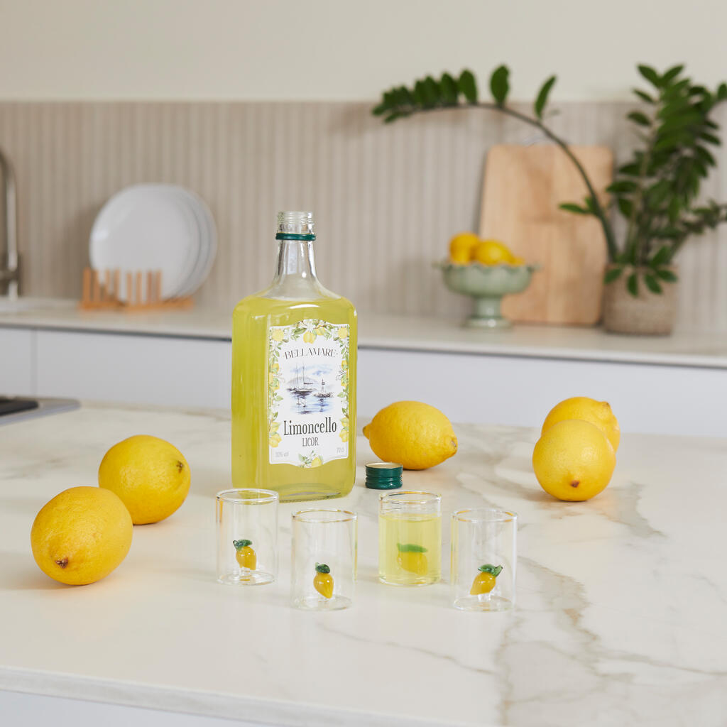 Lemon Shot Glass Set: the filled glasses next to the bottle and lemons on the counter.