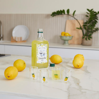 Lemon Shot Glass Set: the filled glasses next to the bottle and lemons on the counter.