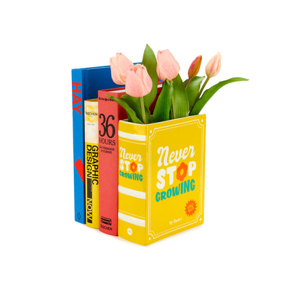 Yellow Book vase with pink tulips next to a stack of real books