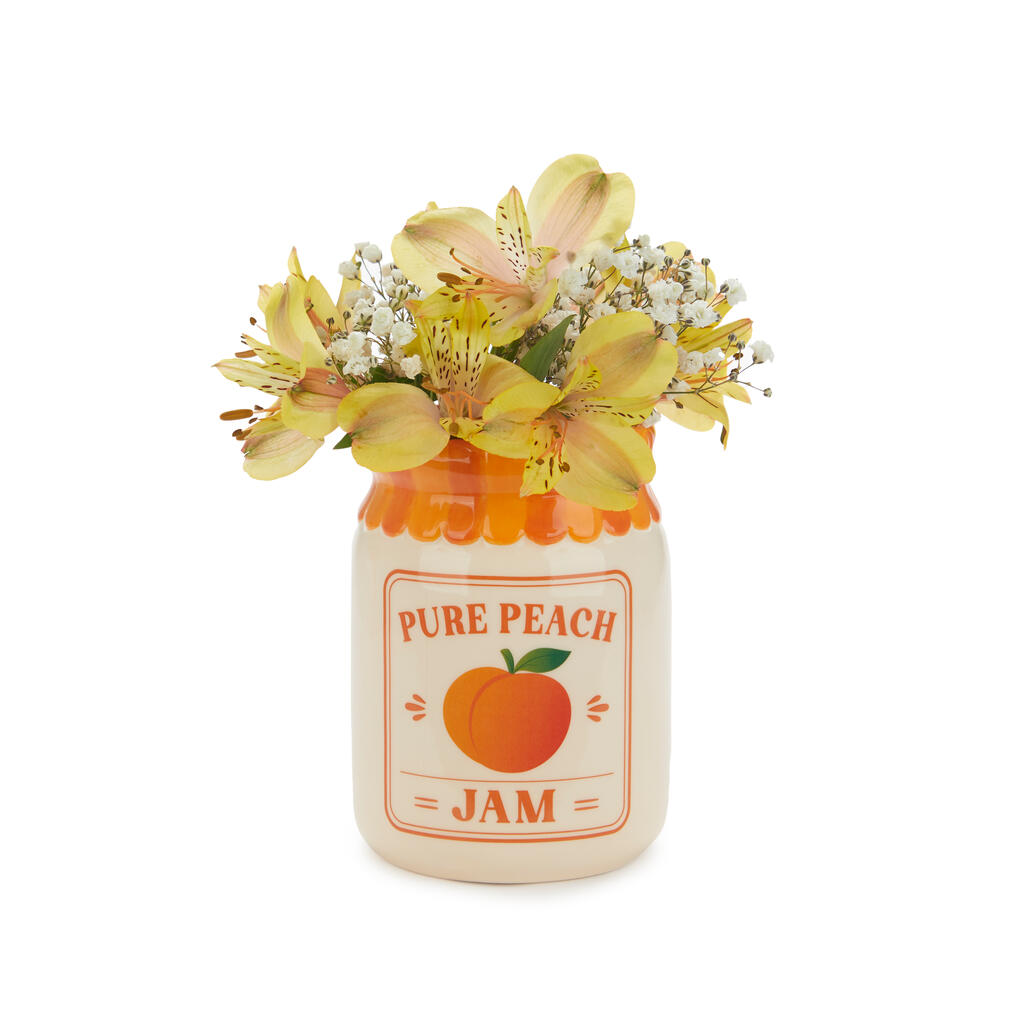 Ceramic jar vase labelled Pure Peach Jam, holding yellow flowers