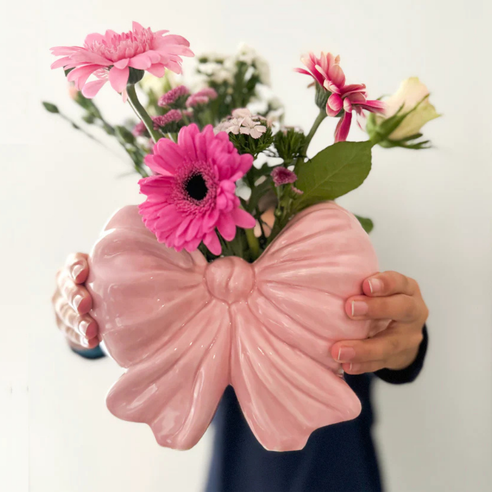 Fiocco bow-shaped vase held in a hand, with a bunch of pink and white flowers.