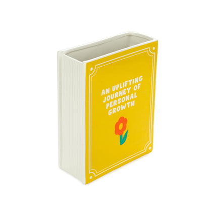 Yellow Book vase empty, with the text "an uplifting journey of personal growth" and a flower
