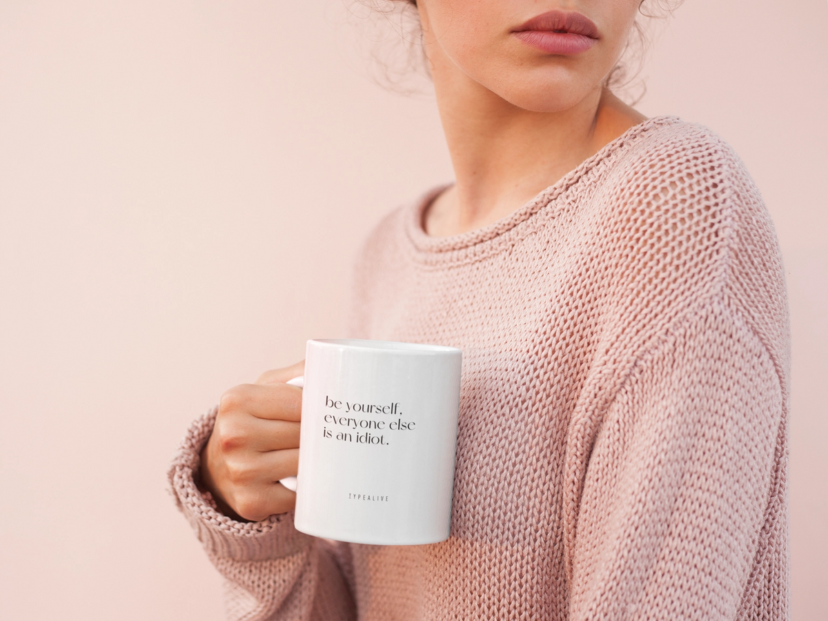 Be Yourself mug in white, held by a person wearing a pink jumper.