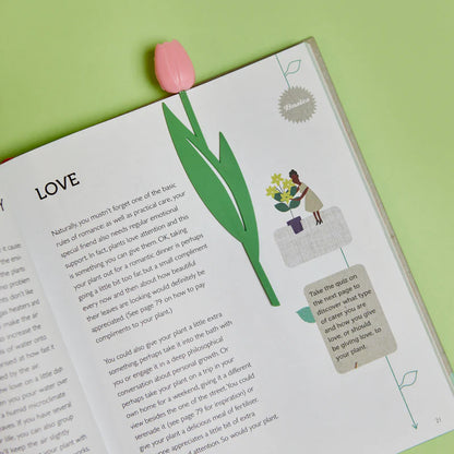 Tulip bookmark placed between the pages of an open book, on a green background.