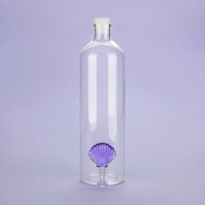 Atlantis Shell bottle, clear glass with a white stopper, on a lilac background