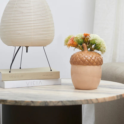 Acorn vase in beige on a side table, with cut flowers next to a paper lamp.