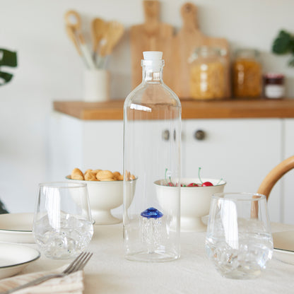 Atlantis Medusa Bottle: the bottle on a set table surrounded by bowls of food.