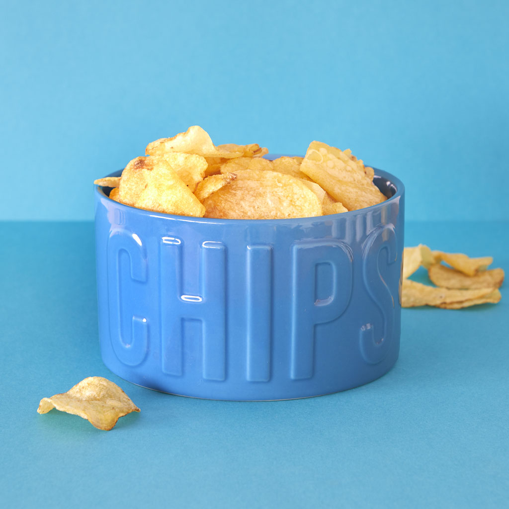 Ciotola Snack Chips azzurra piena di patatine, con alcune sparse sullo sfondo azzurro