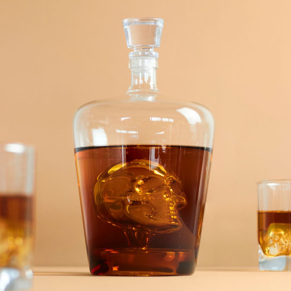 Same Poison decanter on a beige background, with two full glasses beside it