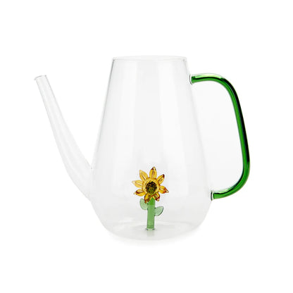 Clear glass watering can with a green handle and a sunflower detail on the glass