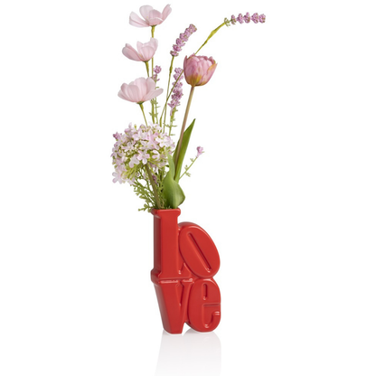 Love vase in red with pink and lilac flowers, shot from a side angle.